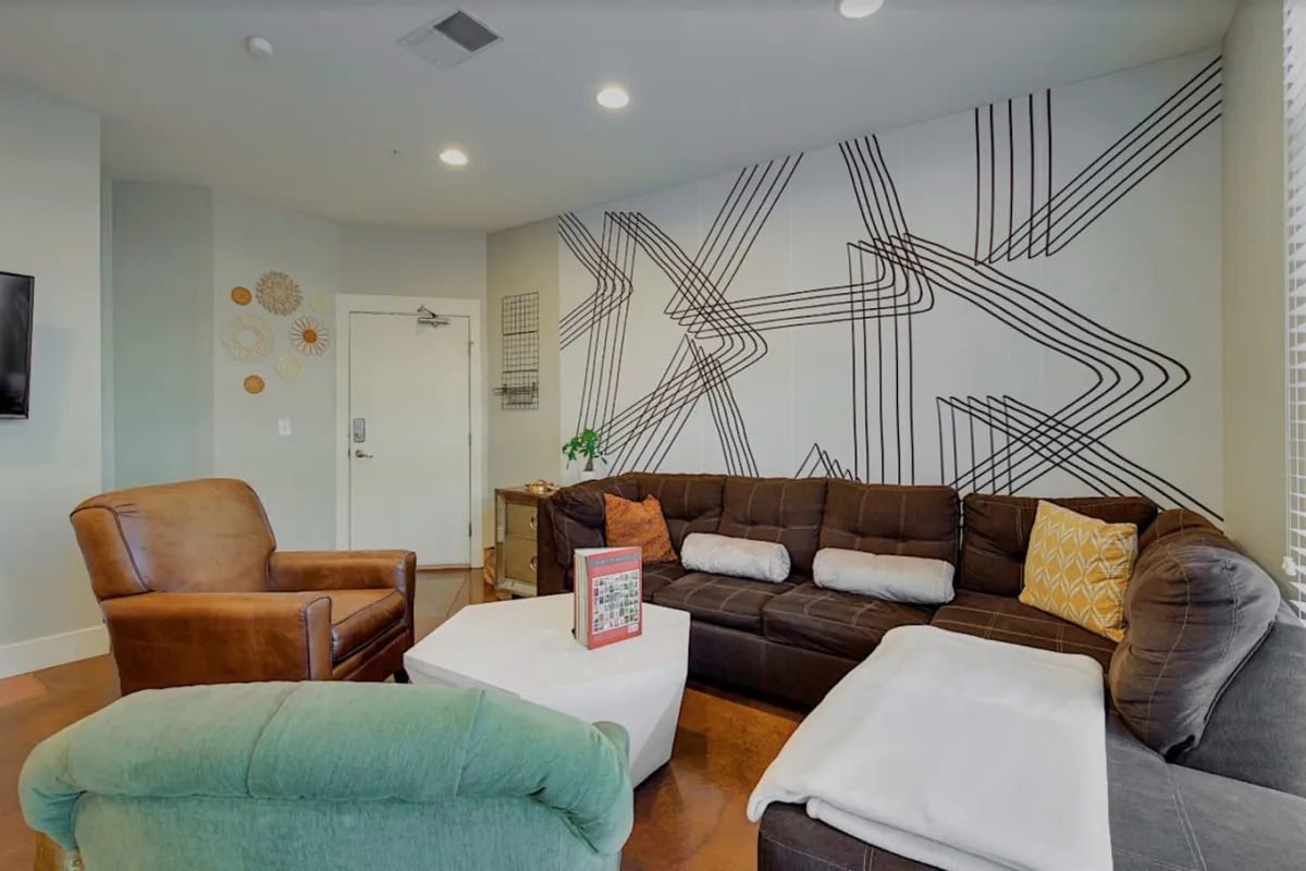 A welcoming living space featuring a comfortable sofa, decorative wall, coffee table, and an armchair. The setup encourages socializing, reading, or enjoying coffee together in a cozy setting.