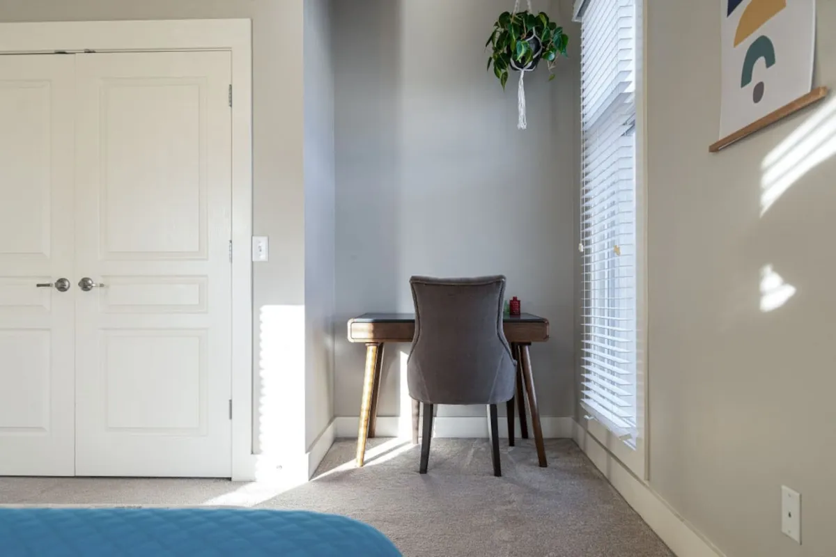Featuring a dedicated workspace, this image shows a desk and chair positioned near a window that lets in plenty of natural light. A potted plant adds a touch of serenity, making the space inviting for working, reading, or quiet contemplation.